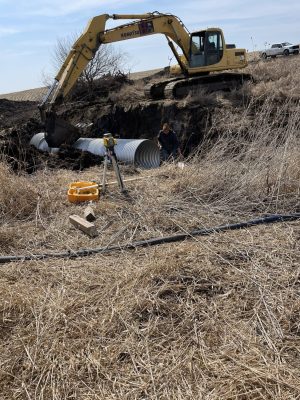 Building site preparation as tractor adds large pipe